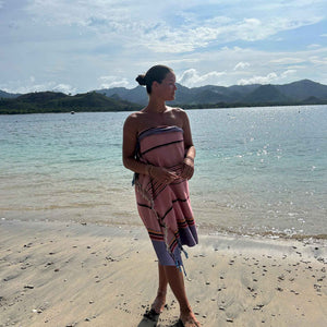 Ein Model trägt das Pestemal Tarifa in Rot als Pareo und steht am Wasserrand am Strand