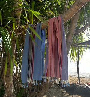 Das Pestemal Tarifa in der Farbe blau und rot hängt von einer Palme am Strand